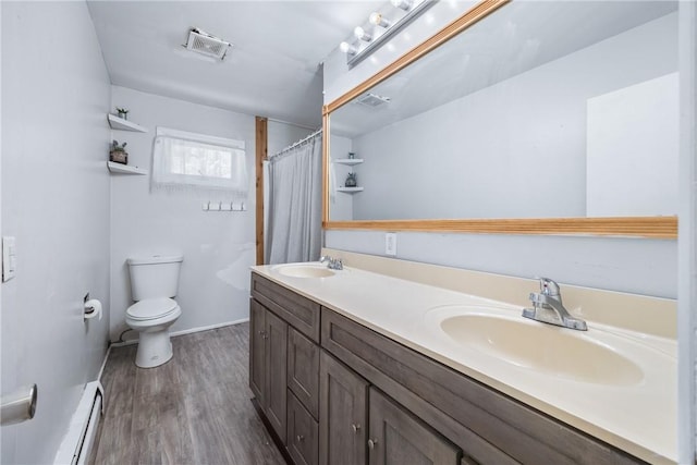 full bath featuring toilet, wood finished floors, a baseboard heating unit, double vanity, and a shower with curtain