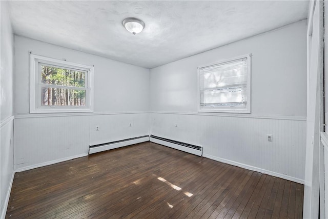 unfurnished room featuring hardwood / wood-style floors, a wainscoted wall, a baseboard heating unit, and baseboards