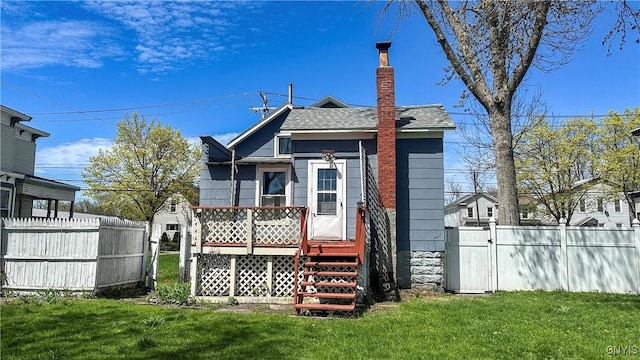 rear view of house featuring a shingled roof, a deck, a gate, and a chimney