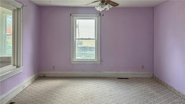 spare room with light colored carpet, ceiling fan, and baseboards