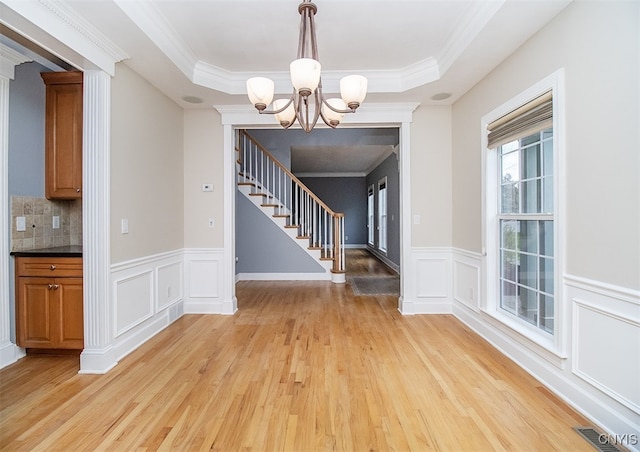 100 Brandywine Dr, Manlius, NY 13104 - unfurnished dining area with stairway, light wood-type flooring, a chandelier, a raised ceiling, and wainscoting