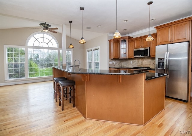 100 Brandywine Dr, Manlius, NY 13104 - kitchen with appliances with stainless steel finishes, brown cabinetry, light wood-style flooring, ceiling fan, and a kitchen breakfast bar