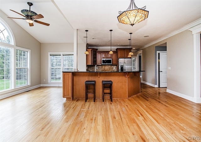 100 Brandywine Dr, Manlius, NY 13104 - kitchen with appliances with stainless steel finishes, a breakfast bar, ceiling fan, light wood finished floors, and baseboards