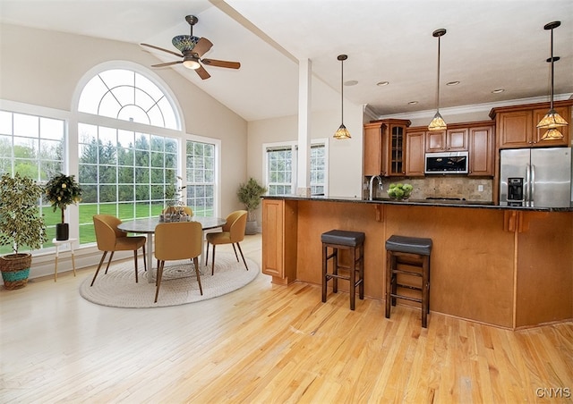 100 Brandywine Dr, Manlius, NY 13104 - kitchen with appliances with stainless steel finishes, brown cabinetry, a ceiling fan, light wood-type flooring, and a breakfast bar