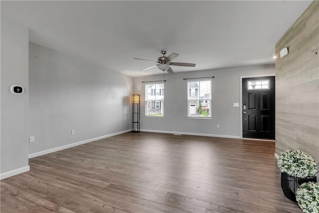 unfurnished living room with a ceiling fan, dark wood-style floors, and plenty of natural light