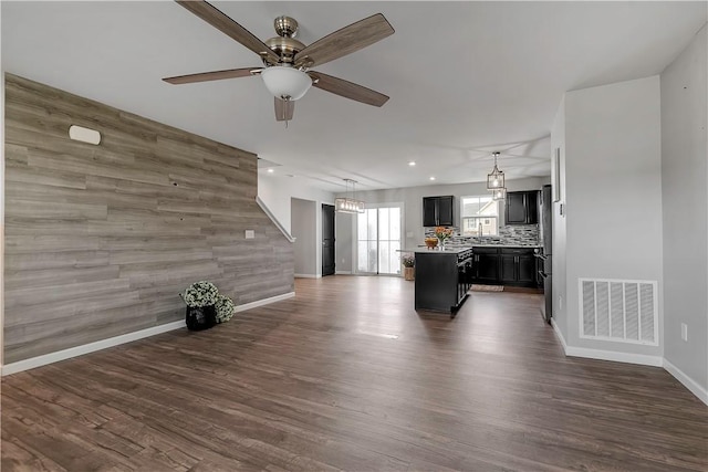 living area featuring baseboards, ceiling fan, dark wood-style flooring, recessed lighting, and an accent wall