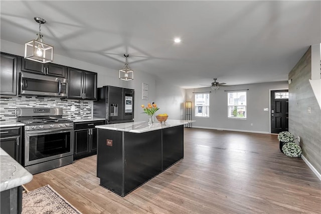 kitchen with stainless steel appliances, dark cabinets, a ceiling fan, baseboards, and open floor plan