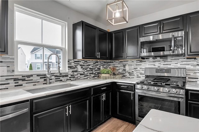 kitchen with appliances with stainless steel finishes, dark cabinetry, a sink, and backsplash