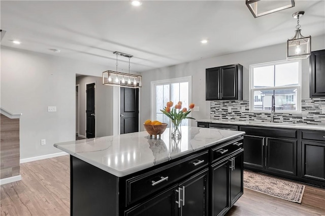 kitchen with dark cabinetry, backsplash, a kitchen island, light wood-style flooring, and recessed lighting