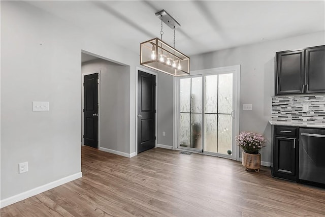 unfurnished dining area featuring a chandelier, light wood-style floors, and baseboards