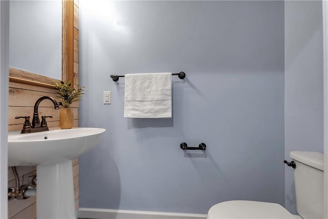 half bathroom featuring toilet, baseboards, and decorative backsplash
