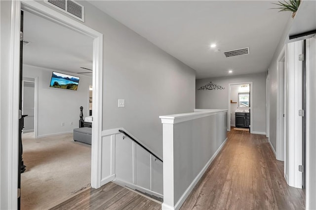 corridor with an upstairs landing, wood finished floors, and baseboards