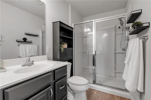 full bath with a stall shower, wood finished floors, vanity, and toilet