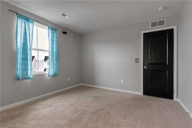 empty room featuring carpet floors, baseboards, and a smoke detector