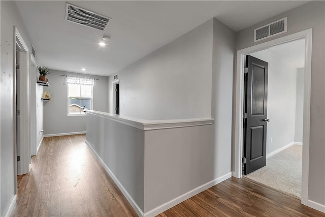 hall with wood finished floors, an upstairs landing, and baseboards