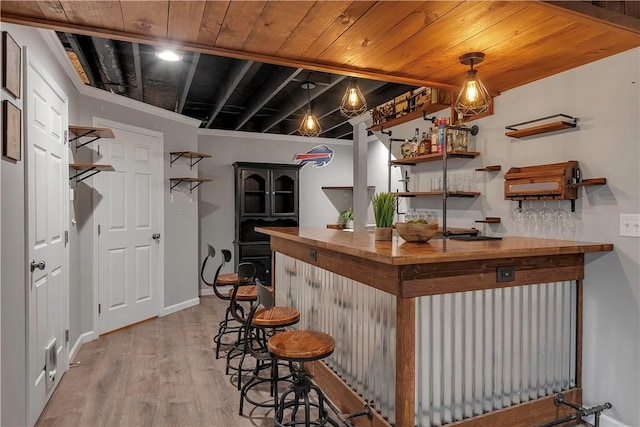 indoor dry bar with light wood-style floors, wooden ceiling, and baseboards