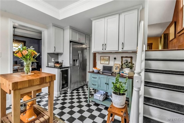 kitchen featuring stainless steel fridge with ice dispenser, tile patterned floors, beverage cooler, white cabinetry, and crown molding