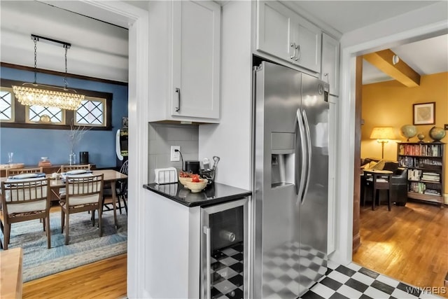 kitchen featuring stainless steel fridge with ice dispenser, beverage cooler, white cabinets, dark countertops, and beam ceiling