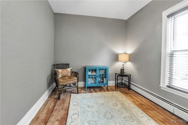 sitting room featuring baseboard heating, wood finished floors, and baseboards