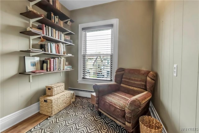 living area with a baseboard radiator, wood finished floors, and baseboards