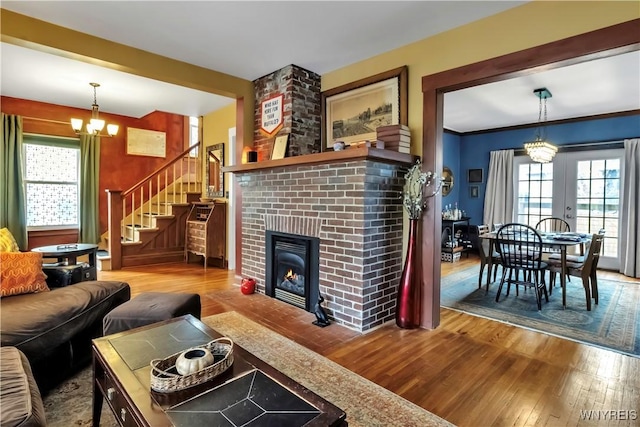 living room with wood finished floors, a chandelier, a fireplace, and stairway