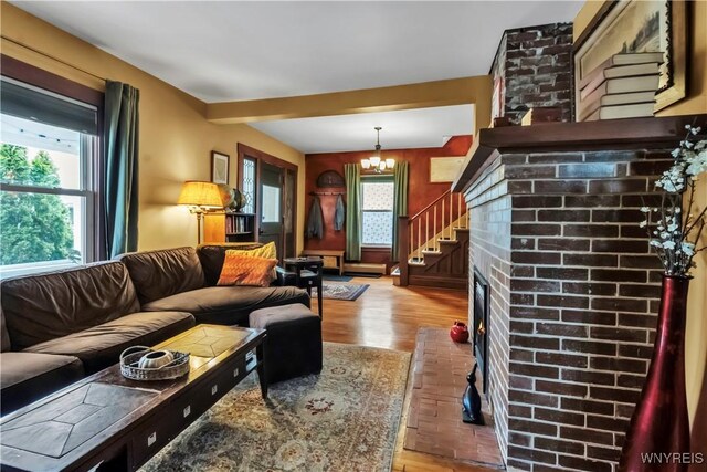 living room with a brick fireplace, a chandelier, and wood finished floors