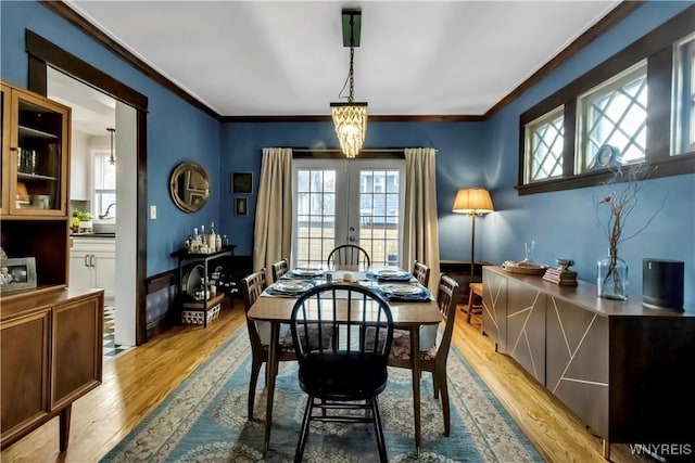 dining area featuring ornamental molding, light wood-type flooring, and a chandelier