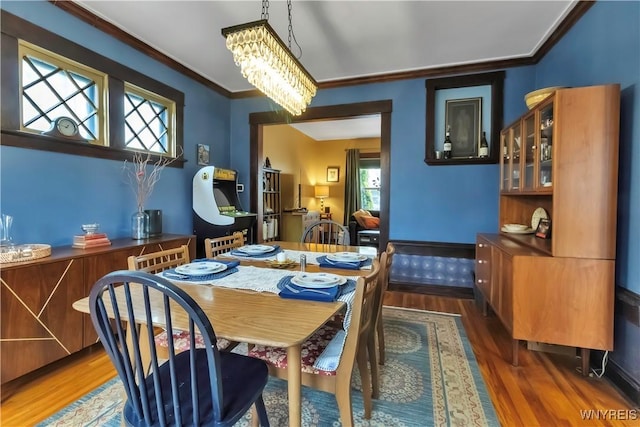 dining room with wood finished floors, crown molding, and a chandelier