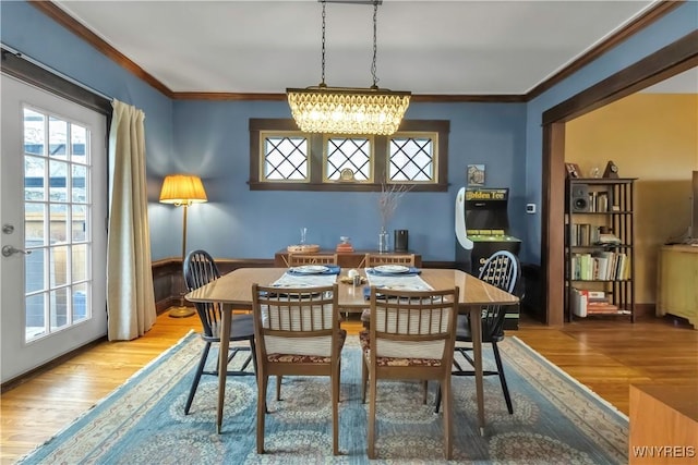 dining space featuring wood finished floors, crown molding, a chandelier, and baseboards