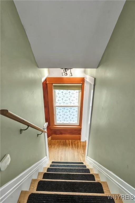 staircase featuring baseboards and wood finished floors