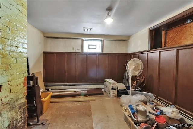 mudroom with a baseboard heating unit, a decorative wall, and wainscoting