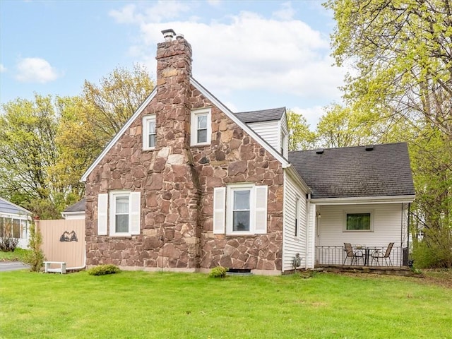 rear view of property with stone siding, a chimney, and roof with shingles