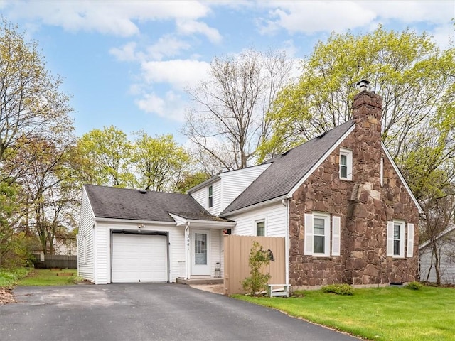 view of front of property featuring stone siding, an attached garage, driveway, a chimney, and roof with shingles