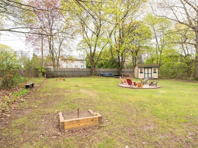 view of yard with a fire pit, a storage unit, an outbuilding, and a vegetable garden
