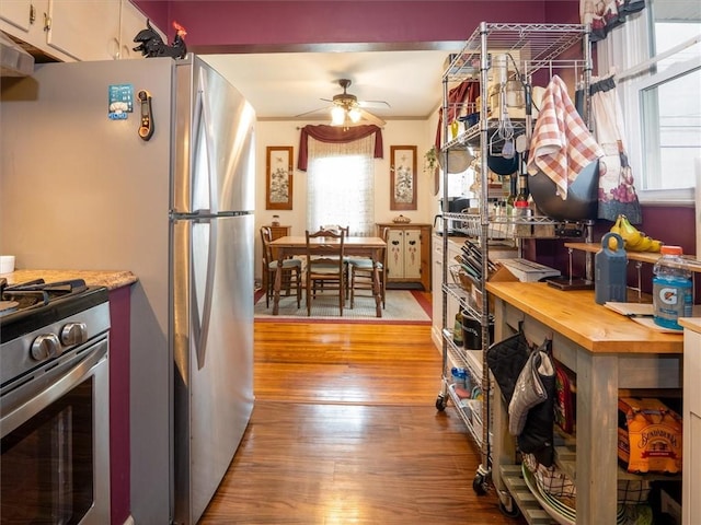 kitchen featuring stainless steel appliances, wood finished floors, ceiling fan, and butcher block counters