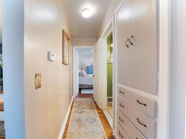 hallway featuring light wood-style flooring and baseboards