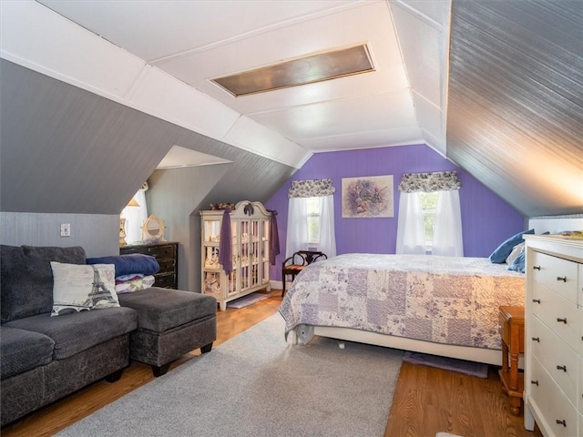 bedroom with wood finished floors and vaulted ceiling