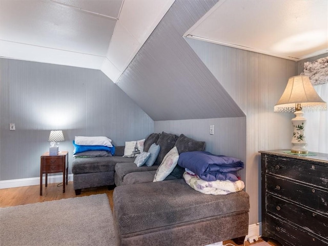 bedroom featuring wood finished floors, lofted ceiling, and baseboards