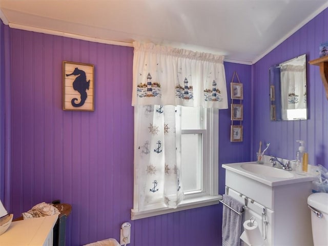 half bath featuring toilet, vanity, and ornamental molding