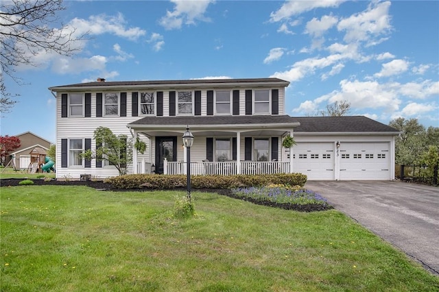 colonial inspired home with asphalt driveway, a porch, an attached garage, a front yard, and a chimney