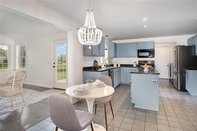 kitchen featuring stainless steel appliances, dark countertops, blue cabinetry, a chandelier, and a kitchen island