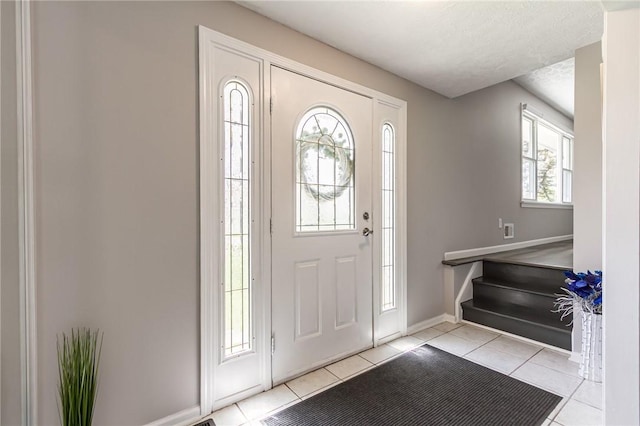 foyer featuring light tile patterned floors, baseboards, and stairway