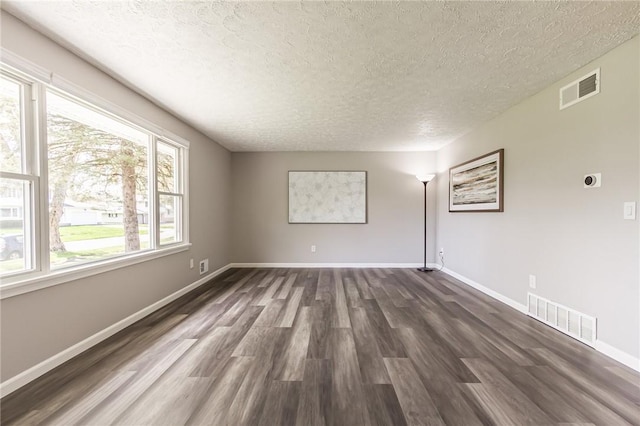 unfurnished room with a textured ceiling, dark wood finished floors, and baseboards