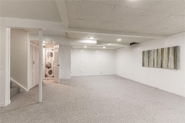 finished below grade area featuring carpet flooring, stairway, and a paneled ceiling