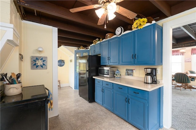 kitchen with blue cabinets, freestanding refrigerator, light countertops, ceiling fan, and stainless steel microwave