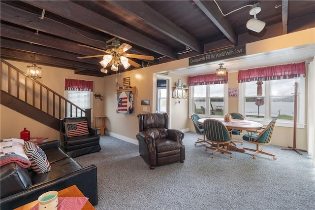 carpeted living room featuring beamed ceiling, stairway, a ceiling fan, and baseboards