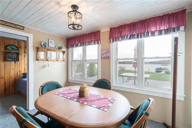 carpeted dining space with a chandelier and wood ceiling