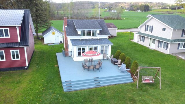 back of property featuring a wooden deck, a chimney, a yard, and outdoor dining space