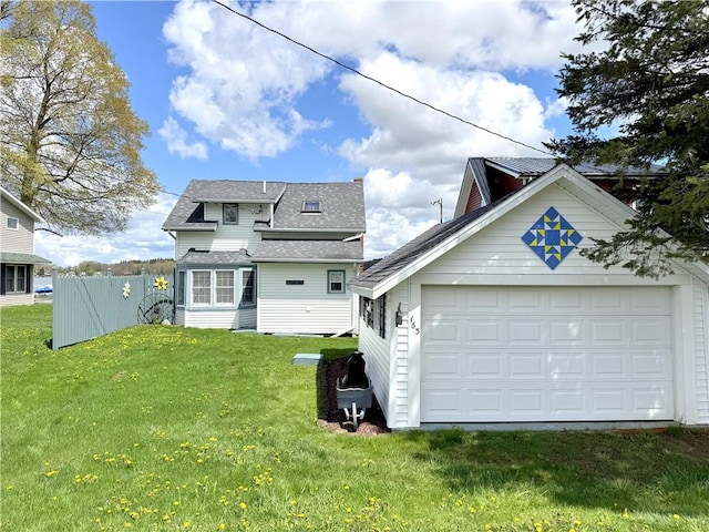 rear view of house featuring roof with shingles and a detached garage