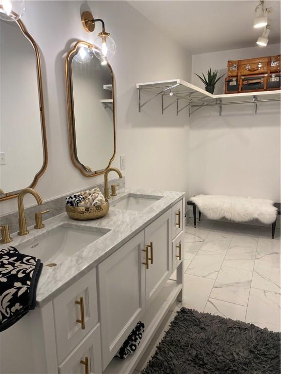 full bath featuring marble look tiles and double vanity
